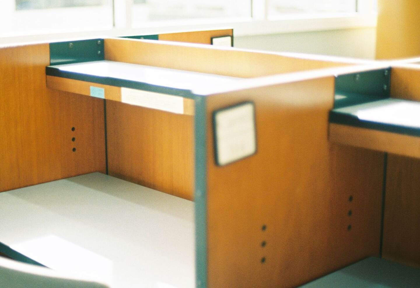 An empty wooden workspace beside a large window with warm natural sunlight